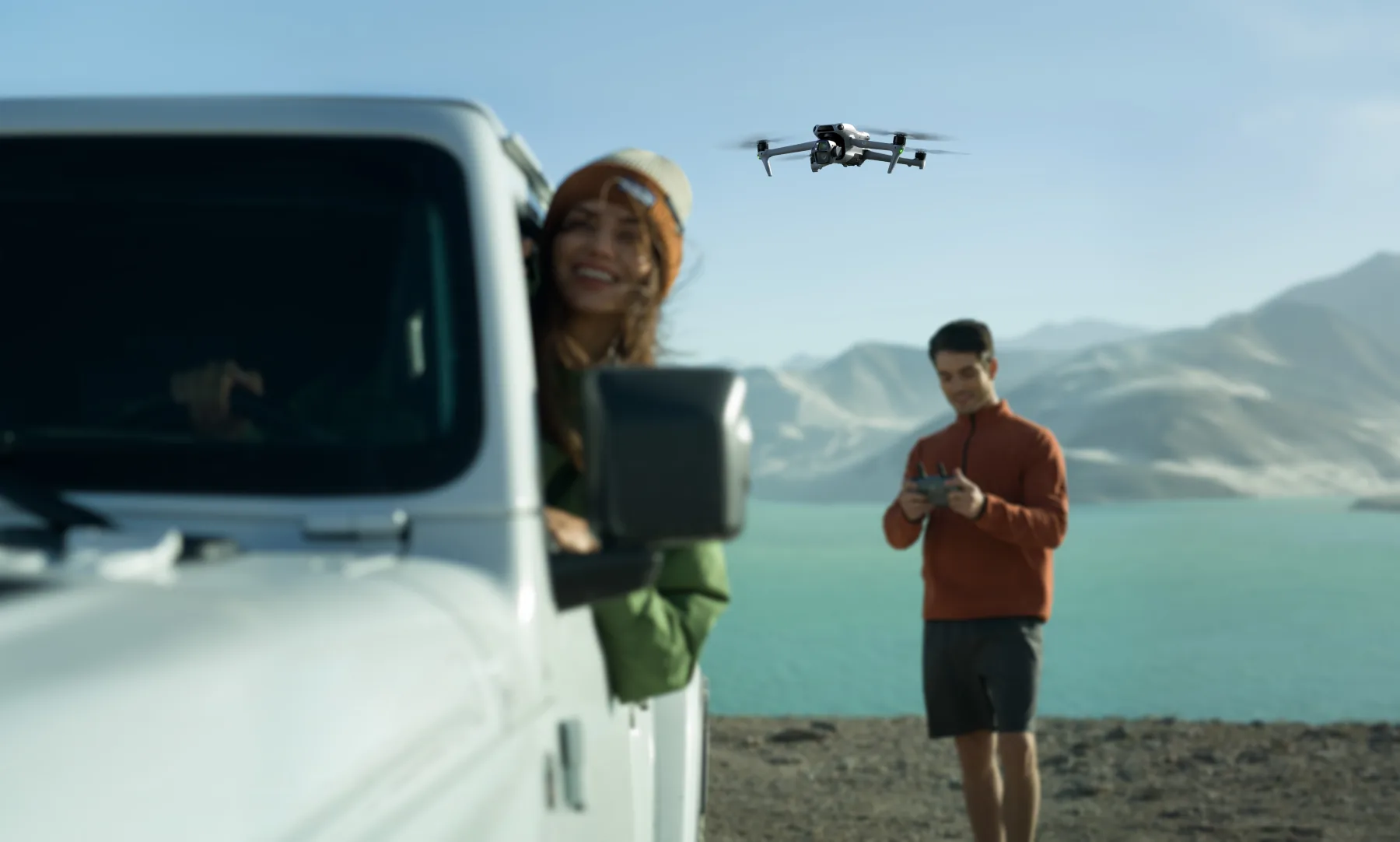 Creator flying a DJI camera drone beside a mountain lake