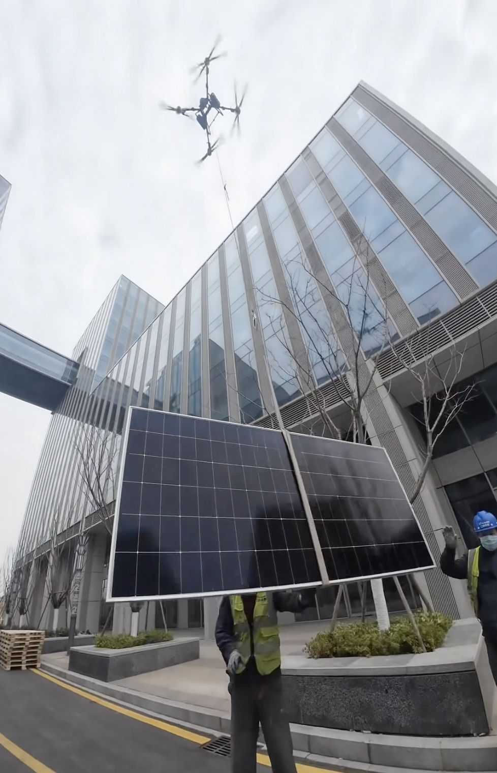 Crew guiding a panel during drone-assisted rooftop handoff